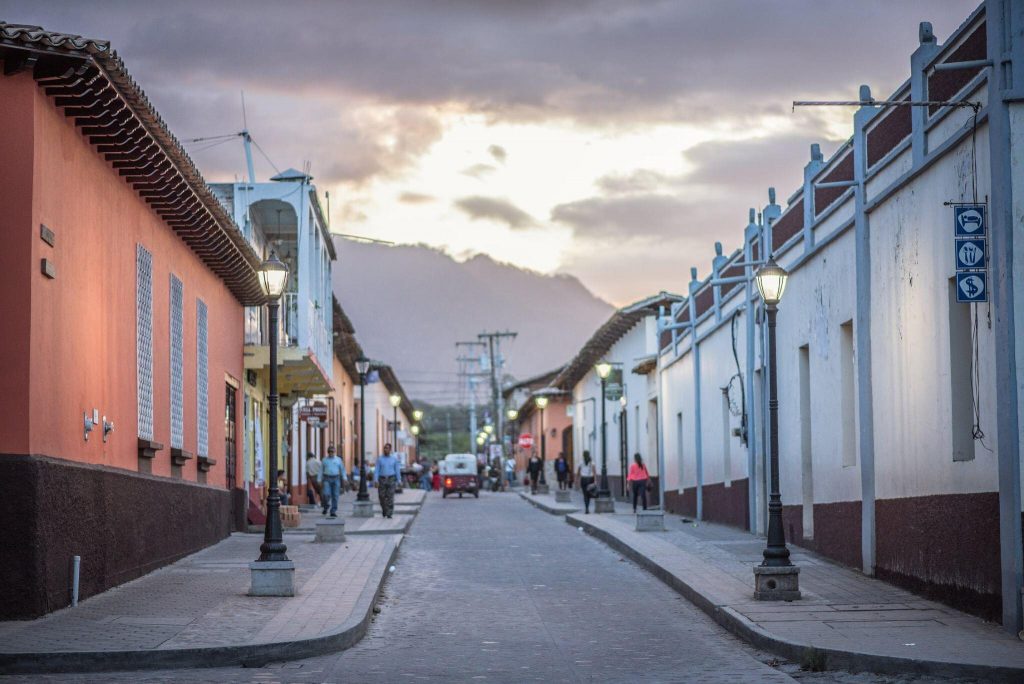 Ancient Mayan temple ruins at Copán with detailed stone carvings and hieroglyphs illuminated by dramatic sunset lighting