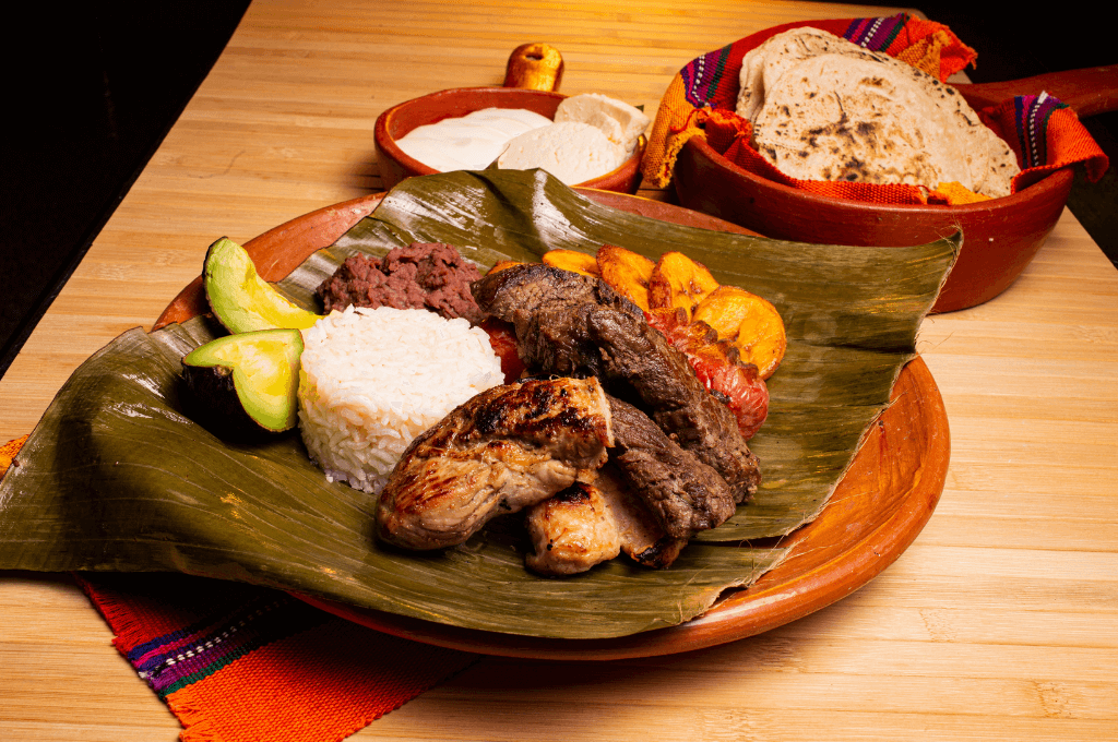 Traditional Honduran feast with baleadas, tamales, and typical dishes arranged on banana leaves with colorful decorations